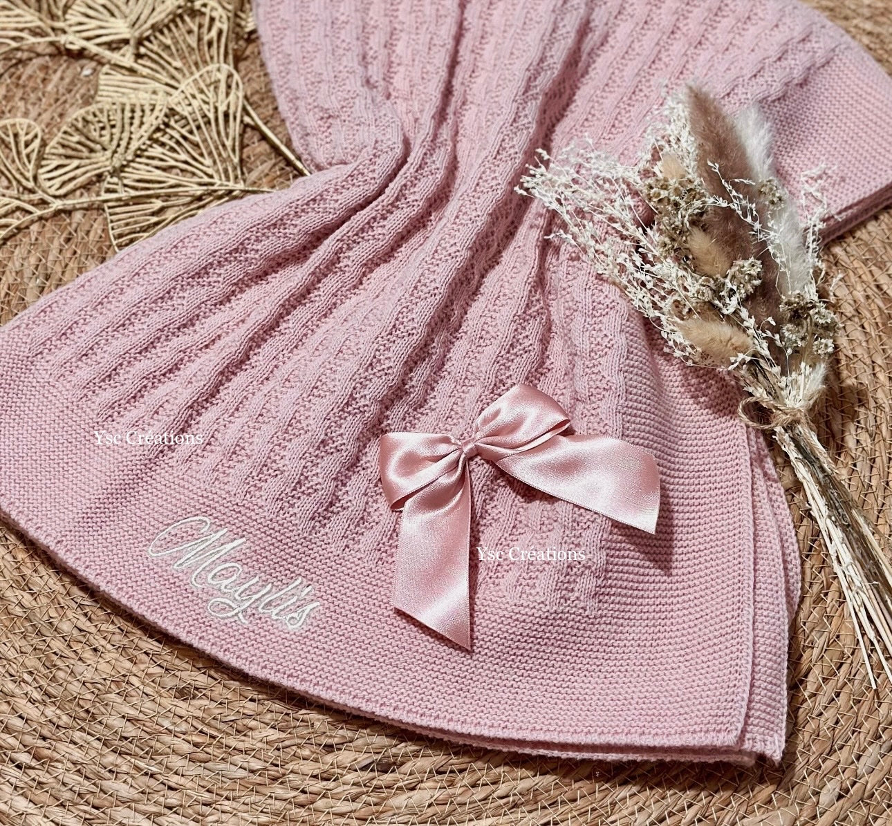 Prénom de bébé brodé sur couverture en maille tricotée vieux rose avec finition nœuds en satin