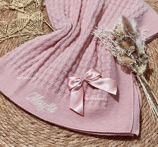 Prénom de bébé brodé sur couverture en maille tricotée vieux rose avec finition nœuds en satin